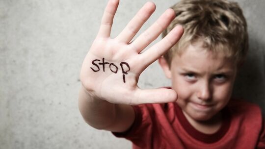 Enfant tendant la main où il y est écrit STOP.